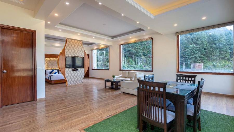 Image of a spacious suite with a dining area, a sitting area with a sofa, and large windows offering scenic views  | DLS Serenity Resort and Spa